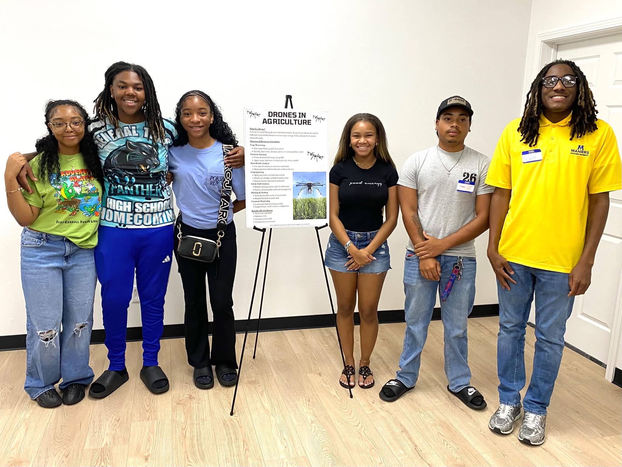 Two young men with a group of teenagers posing for a picture.